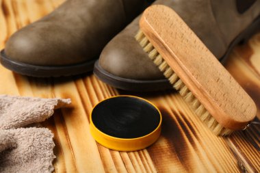 Ahşap arka planda fırça, bot, kumaş ve ayakkabı cilası.