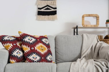 Oturma odasında yastıklı ve ekoseli gri kanepe.