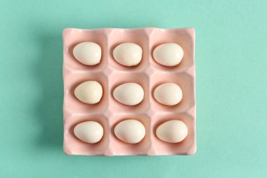 Turkuaz arka planda taze haşlanmış bıldırcın yumurtalı tutucu.