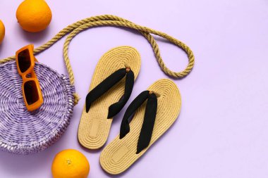Pipet çantalı terlikler, mor arka planda güneş gözlüğü ve portakallar.