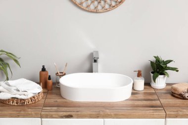 Modern lavabo ve banyo malzemeleri banyodaki ışıklı duvarın yanındaki ahşap çekmecelerde.