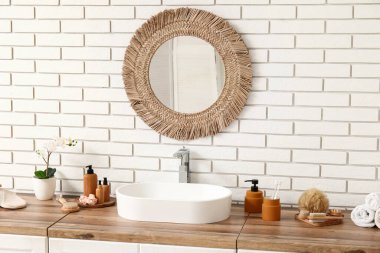 Lavabo, banyo malzemeleri ve banyodaki beyaz tuğla duvarda ayna olan çekmeceler.
