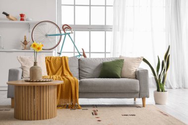 Gri koltukları, kahve masası ve bisikleti olan şık bir oturma odası.