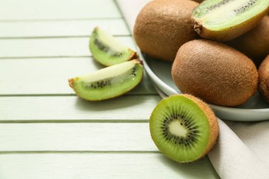 Yeşil ahşap arka planda taze kivi tabağı.