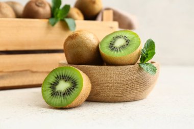 Beyaz arka planda taze kivi ile ahşap kase ve kutu.