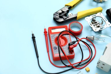 Multimetre, elektrikçi aletleri ve mavi arka planda ampul