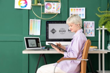 Ofiste tabletle çalışan genç bayan grafik tasarımcısı