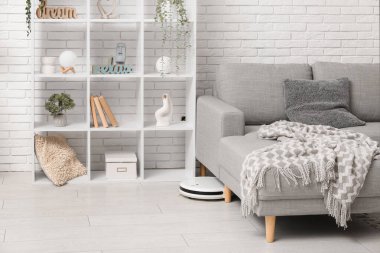 Evdeki koltuğun altındaki modern robot süpürgesi.