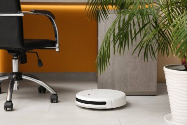 Evdeki masanın yanındaki modern robot elektrikli süpürge.