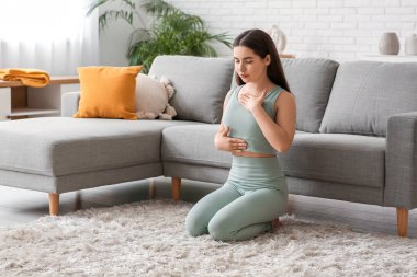 Evde nefes egzersizi yapan güzel bir genç kadın.