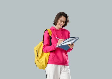 Işık arkaplan üzerine not defterine yazan güzel öğrenci