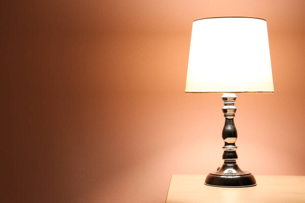 Светящаяся лампа на деревянном столе в темной комнате