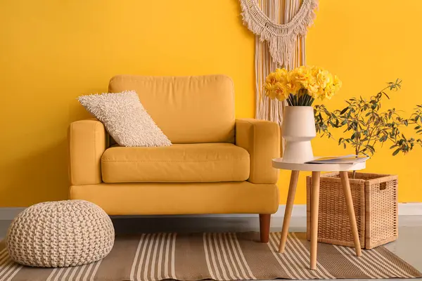 Oturma odasının içinde güzel narsist çiçekleri olan rahat bir koltuk ve vazo.