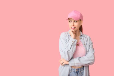Beautiful young woman in stylish cap on pink background