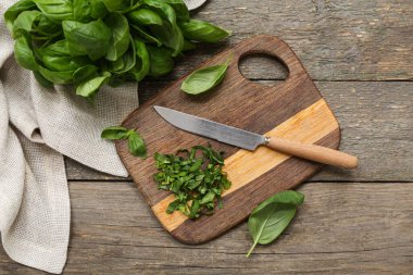 Ahşap zemin üzerinde taze fesleğen yaprakları kesilmiş bir tahta.