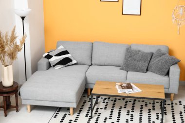 Güzel oturma odasının içinde rahat bir kanepe, halı, lamba ve kahve masası.