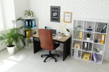 Çalışma odası, kahverengi koltuk, modern dizüstü bilgisayar ve raf ünitesi.