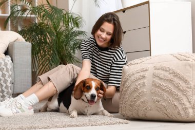 Genç bir kadın evde sevimli bir tazıyla yerde oturuyor.