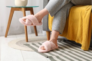 Pembe terlikli genç bir kadın. Odada koltukta oturuyor. Yakın plan.