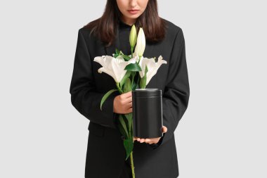 Morg vazosu ve beyaz arka planda zambak demeti olan genç kadın, yakın plan.