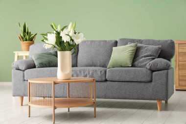 Sehpanın üzerinde zambak demeti, yastıklar ve rahat bir kanepe olan şık bir oturma odası.