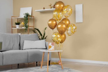Evdeki bej duvarın yanında kanepesi ve sehpası olan güzel altın hava balonları.