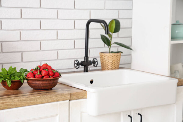 Bowls with tasty strawberries and mint on counter in kitchen