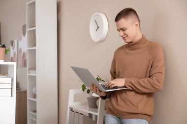 Hafif ev ofisinde dizüstü bilgisayarı olan genç bir serbest çalışan.