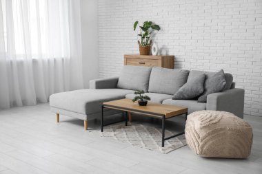 Oturma odasının içinde yastıklı, puf ve sehpalı rahat bir kanepe.