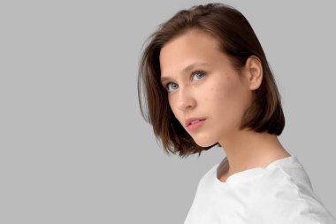 Gri arka plan üzerinde akne problemi olan güzel kadın