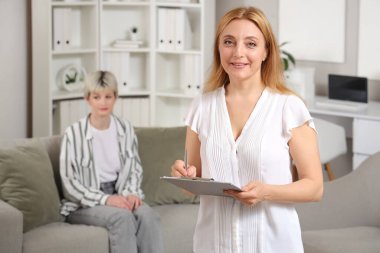 Ofisinde panosu olan genç bir kadın psikolog.