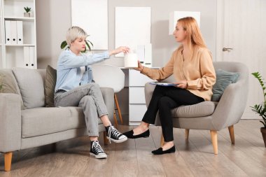 Ofiste ağlayan genç kıza peçete veren kadın psikolog.