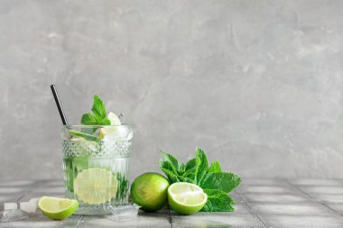 Bir bardak taze mojito kokteyli, limonlu ve naneli gri fayanslı.