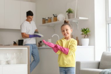Lastik eldivenli şirin küçük kız ve babası mutfakta.