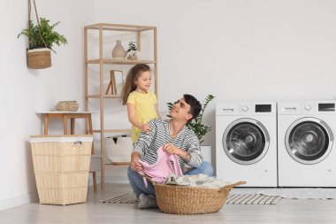 Genç baba ve kızı banyoda çamaşır sepetiyle