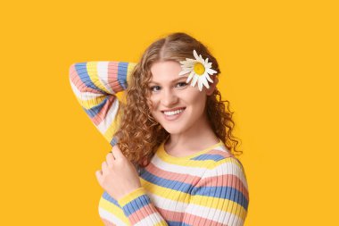 Sarı arka planda papatya çiçeği olan güzel genç bir kadın.