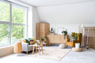 Gri kanepesi, koltuğu ve çekmeceleri olan aydınlık oturma odasının içi.