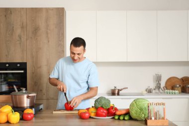 Genç adam mutfakta dolma biber kesiyor.