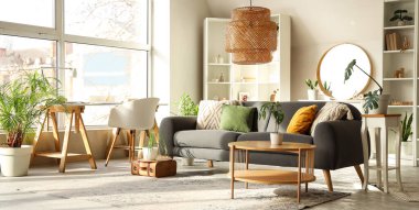 Gri kanepesi, masası, işyeri, raf ünitesi ve aynası olan şık bir oturma odası.