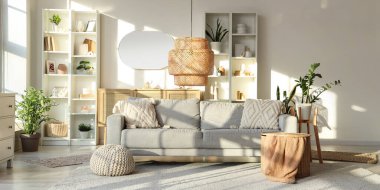 Gri kanepeli, raf üniteli ve aynalı aydınlık oturma odasının içi.