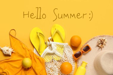 Parmak arası terlik, mayo, güneş gözlüğü ve sarı arka planda hasır şapka.