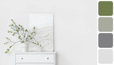 Beyaz odadaki çekmecelerin üzerinde çiçek açan ağaç dalları olan vazo. Farklı renk desenleri