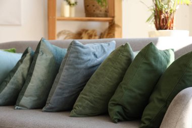 Modern oturma odasındaki gri koltukta şık yastıklar, yakın plan.