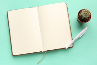 Renk arkaplan üzerinde boş açık defter, kalem ve ev bitkisi