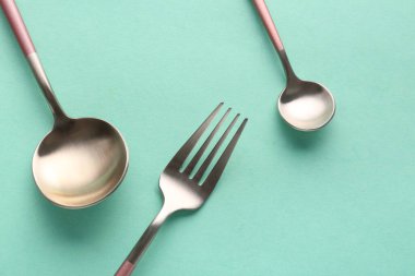 Yeşil arka planda şık çatal ve kaşıklar