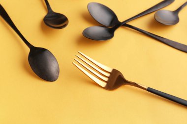 Sarı arka planda şık çatal ve kaşıklar