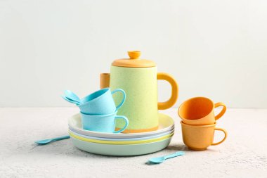 Bardaklı tabaklar, çaydanlık ve bebek için kaşıklar grunge beyaz masa