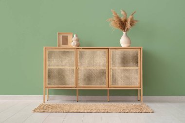 Oda yeşil duvarın yanında otlu ve dekorlu modern çekmeceler.