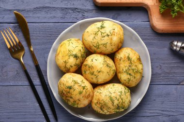 Mavi ahşap arka planda dereotlu haşlanmış bebek patatesler.