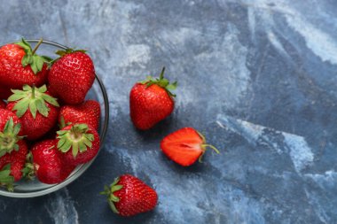 Mavi arka planda taze çilekli cam kase.